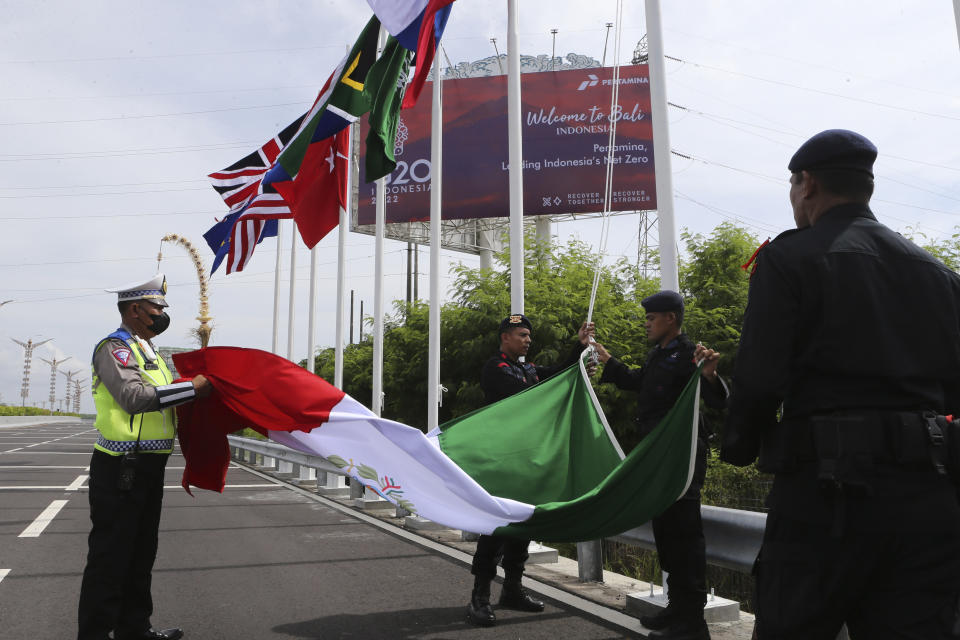 Police officers prepare to hoist a Mexican flag along with the flags of other G20 countries, on a road leading to the venue of the G20 Summit in Nusa Dua, Bali, Indonesia on Saturday, Nov. 12, 2022. A showdown between Presidents Joe Biden and Vladimir Putin isn't happening, but the fallout from Russia's invasion of Ukraine and growing tensions between China and the West will be at the forefront when leaders of the world's biggest economies gather in tropical Bali this week.(AP Photo/Firdia Lisnawati)