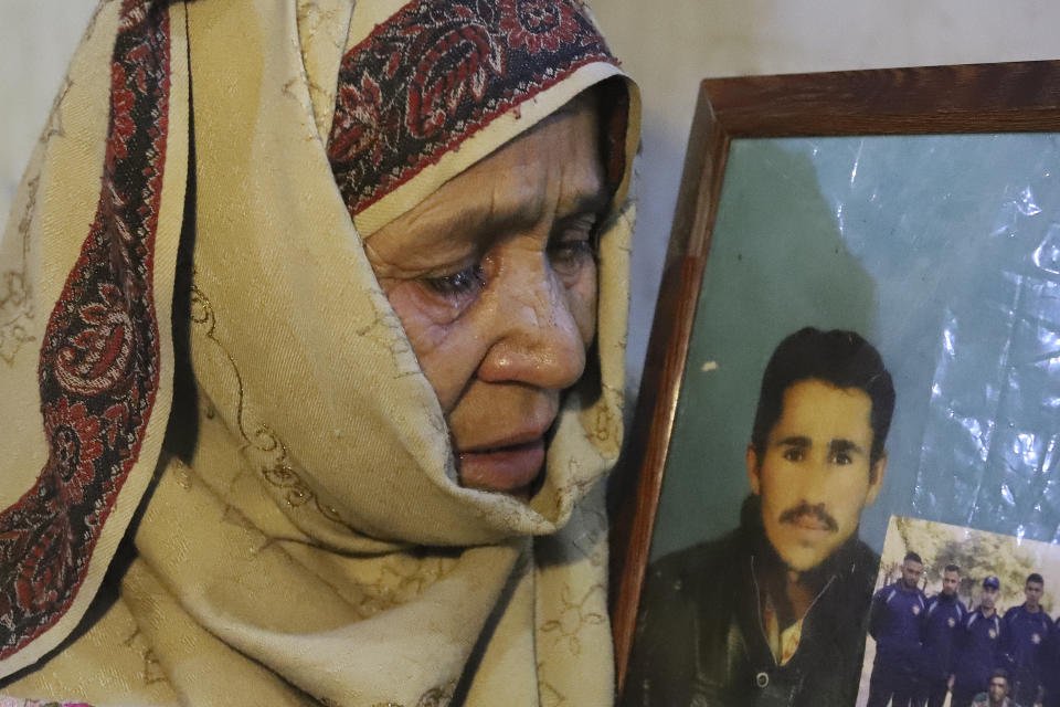 The mother of Mohammed Hassan, a Pakistani porter who died on July 27 during a summit of K2, weeps while she holds a portrait of him at their home in Tasar, a village in the Shigar district in the Gilgit-Baltistan region of northern Pakistan, Saturday, Aug. 12, 2023. An investigation has been launched into the death of a Hassan near the peak of the world's most treacherous mountain, a Pakistani mountaineer said Saturday, following allegations that dozens of climbers eager to reach the summit had walked past the man after he was gravely injured in a fall. (AP Photo/M.H. Balti)