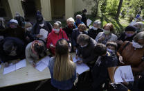 People line up to fill in forms before getting tested for the coronavirus in Prague, Czech Republic, Thursday, April 23, 2020. Czechs have been forming long lines to get tested in a study to determine undetected infections with the coronavirus in the population. Some 27,000 people aged 18 - 89 across the country will be tested in the next two weeks, starting on Thursday. (AP Photo/Petr David Josek)