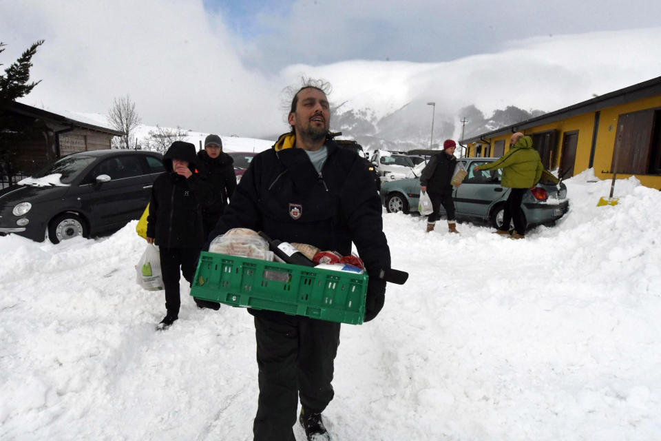 Residents carry food and goods brought by Italian army's vehicles in the village of Campotosto, in the mountainous region of central Italy that has been struck by a series of quakes since August that destroyed historic centers in dozens of towns and hamlets, Thursday, Jan. 19, 2017. Rescue workers were met with an eerie silence Thursday when they reached a four-star spa hotel struck by an avalanche in a mountainous earthquake-stricken region of central Italy. At least 30 people were missing, including at least two children, authorities said. (Claudio Lattanzio/ANSA via AP)