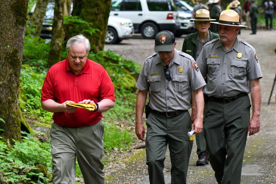 This Wednesday, May 6, 2020 image from a tweet by Interior Secretary David Bernhardt, the Interior Secretary visits with National Parks Service employees at Great Smoky Mountains National Park. While the Interior Secretary asked visitors to social distance when the park reopens on May 9, neither Bernhardt nor park staff wore face masks in the photos, as they talked and walked inches apart during his visit on Tuesday, May 5. (National Parks Service via AP)