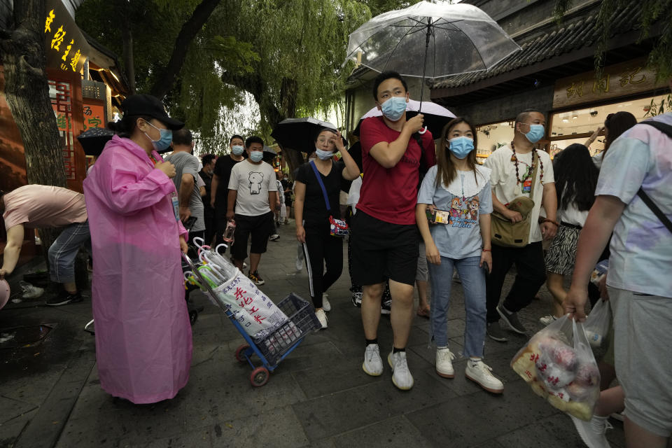 Visitors pass through the popular Nanluoguxiang alley way in Beijing on Saturday, July 3, 2021. A small but visible handful of urban Chinese are rattling the ruling Communist Party by choosing to "lie flat," or reject high-status careers, long work hours and expensive cities for a "low-desire life." That clashes with party ambitions to make China a wealthier consumer society. (AP Photo/Ng Han Guan)