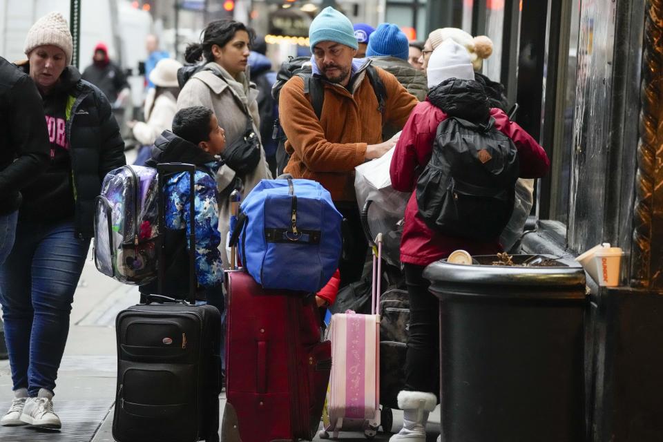 An immigrant family stands outside the Roosevelt Hotel with their belongings, Tuesday, Jan. 9, 2024, in New York. (AP Photo/Mary Altaffer)