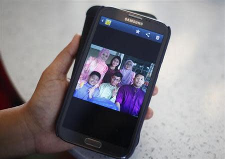 Arni Marlina, 36, a family member of a passenger onboard the missing Malaysia Airlines flight MH370, shows a family picture on her mobile phone, at a hotel in Putrajaya March 9, 2014. REUTERS/Samsul Said