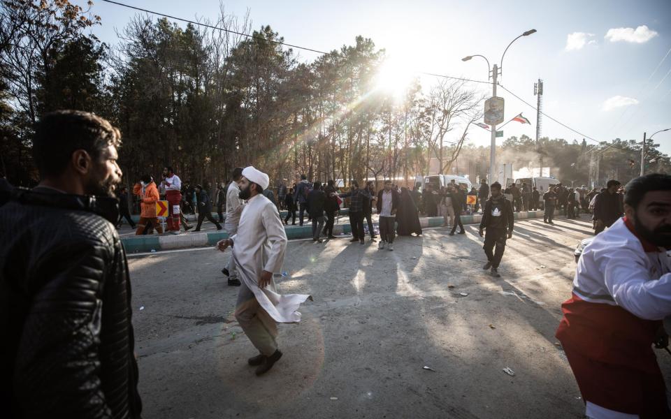 People try to help victims after explosions during a commemoration ceremony next to the tomb of Iran's Revolutionary Guards chief of foreign operations Iranian General Qasem Soleimani in the Saheb al-Zaman mosque in the southern city of Kerman, Iran