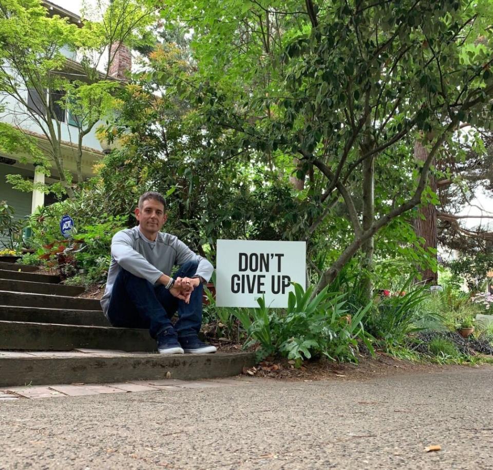 Seattle father Colby Wallace is pictured with one of the signs he has put up to help stop suicides. 