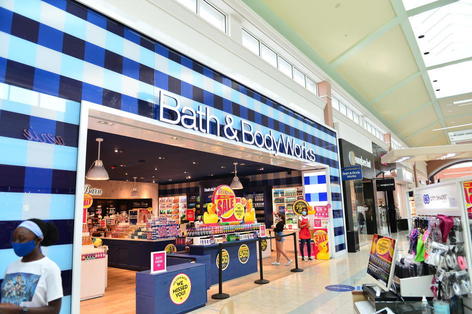 Exterior view of Bath & Body Works store in a mall with promotional signs and customers entering