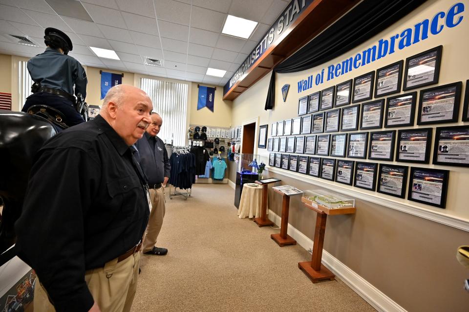 Volunteer Paul Landry and Steve Byron, president of the board of directors, look over the Wall of Remembrance of troopers who died on the job.