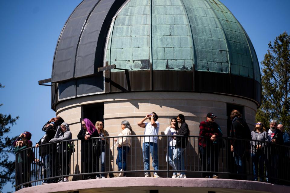 Iowans look to the sky through their solar eclipse glasses as the eclipse reaches its peak Monday, April 8, 2024, at the Drake Municipal Observatory.