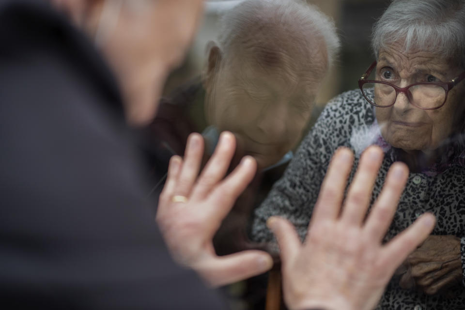 Javier Anto, 90, reacts in front of his wife Carmen Panzano, 92, through the window separating the nursing home from the street in Barcelona, Spain, Wednesday, April 21, 2021. Since the pandemic struck, a glass pane has separated _ and united _ Javier and Carmen for the first prolonged period of their six-decade marriage. Anto has made coming to the street-level window that looks into the nursing home where his wife, since it was closed to visits when COVID-19 struck Spain last spring. (AP Photo/Emilio Morenatti)