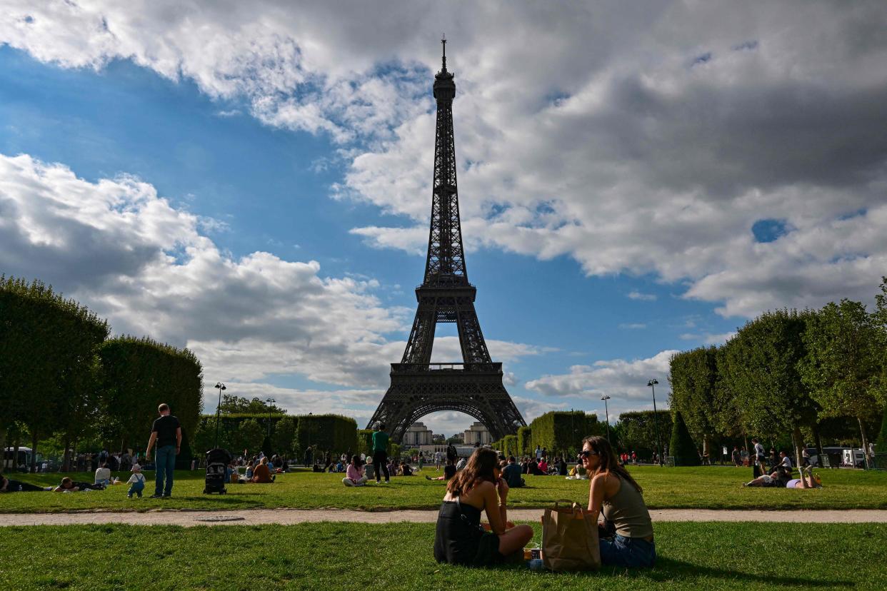 Tourists and Parisians are photographed in August sitting in the Champ de Mars in front of the Eiffel Tower in Paris.