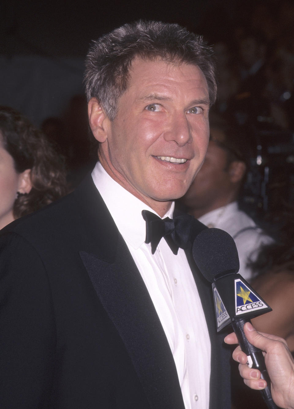 Harrison Ford in a tuxedo being interviewed on the red carpet