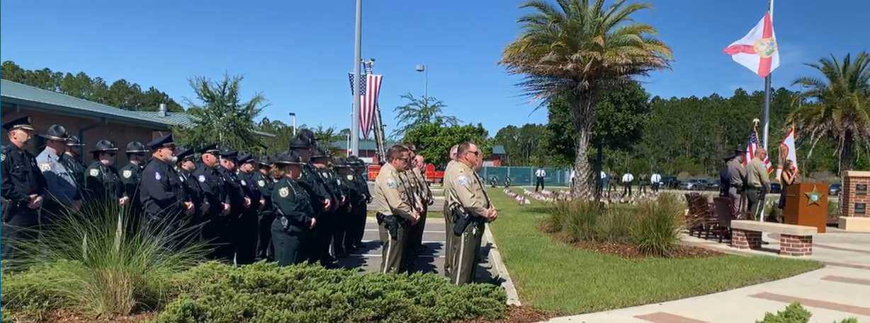 The Nassau County law enforcement community stands in honor of fallen comrades as Katio O, right, at podium, sings "Amazing Grace" Wednesday outside the Sheriff's Office.