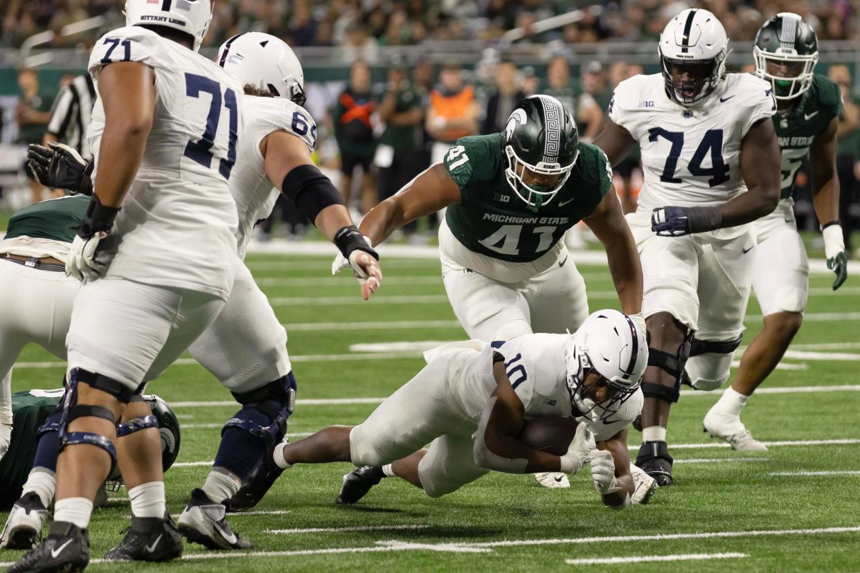 Penn State running back Nicholas Singleton runs with the ball while defended by Michigan State defensive lineman Derrick Harmon during the first half on Friday, Nov. 24, 2023, at Ford Field.