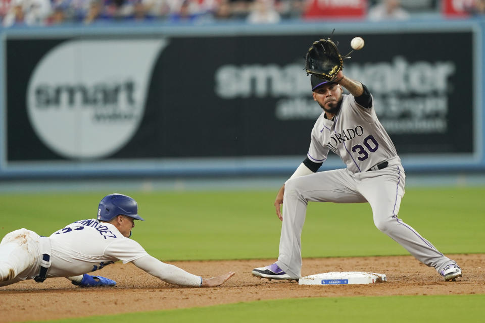 Colorado Rockies second baseman Harold Castro (30) waits for a pickoff throw as Los Angeles Dodgers' Kiké Hernandez dives back during the second inning of a baseball game Friday, Aug. 11, 2023, in Los Angeles. (AP Photo/Ryan Sun)