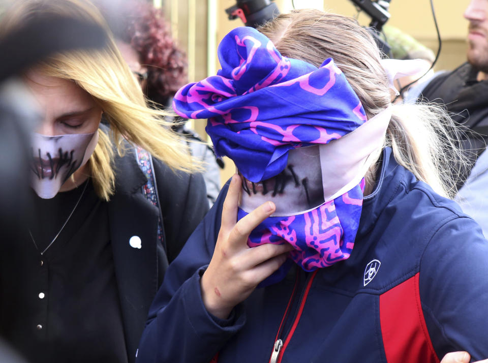 A 19-year old British woman, right, covers her face as she leaves from the Famagusta court after her trial, in Paralimni, Cyprus, Monday, Dec. 30, 2019. A Cyprus court on Monday found a 19 year-old British woman guilty of fabricating claims that she was gang raped by 12 Israeli men. (AP Photo/Philippos Christou)