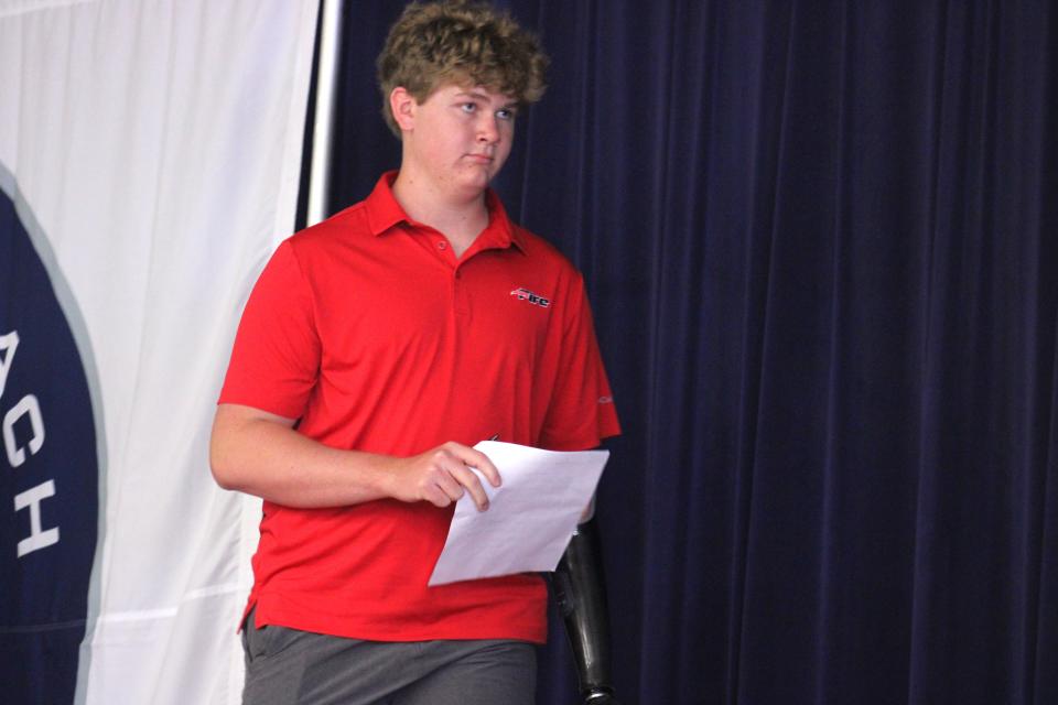 With a prosthetic left hand and his college letter of intent with Southeastern University in his right, Nolan Blackard stands on stage at Fernandina Beach High School during a college athletic signing ceremony on May 1, 2024. [Clayton Freeman/Florida Times-Union]