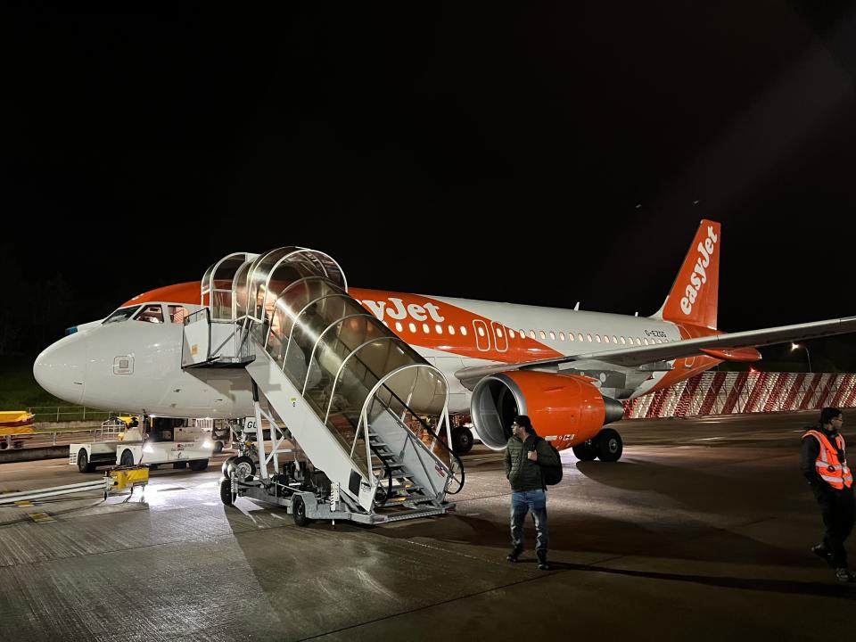 A passenger disembarks an easyJet Airbus A319 at nighttime