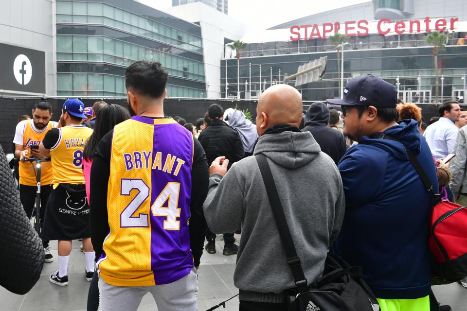 People gather around a makeshift memorial for former NBA and Los Angeles Lakers player Kobe Bryant after learning of his death at LA Live plaza in front of Staples Center in Los Angeles on January 26, 2020. - NBA legend Kobe Bryant died January 26, 2020 in a helicopter crash in suburban Los Angeles, celebrity website TMZ reported, saying five people are confirmed dead in the incident. (Photo by Frederic J. Brown / AFP) (Photo by FREDERIC J. BROWN/AFP via Getty Images)