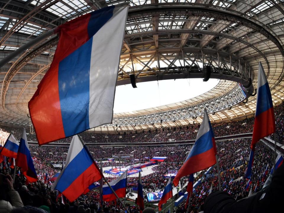 People wave Russian flags during a concert marking the eighth anniversary of Russia's annexation of Crimea (via REUTERS)