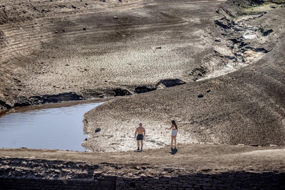 La gente camina sobre la tierra seca y agrietada en el embalse de Baitings en Ripponden, West Yorkshire, donde los niveles de agua son significativamente bajos (Danny Lawson/PA).  (Cable PA)