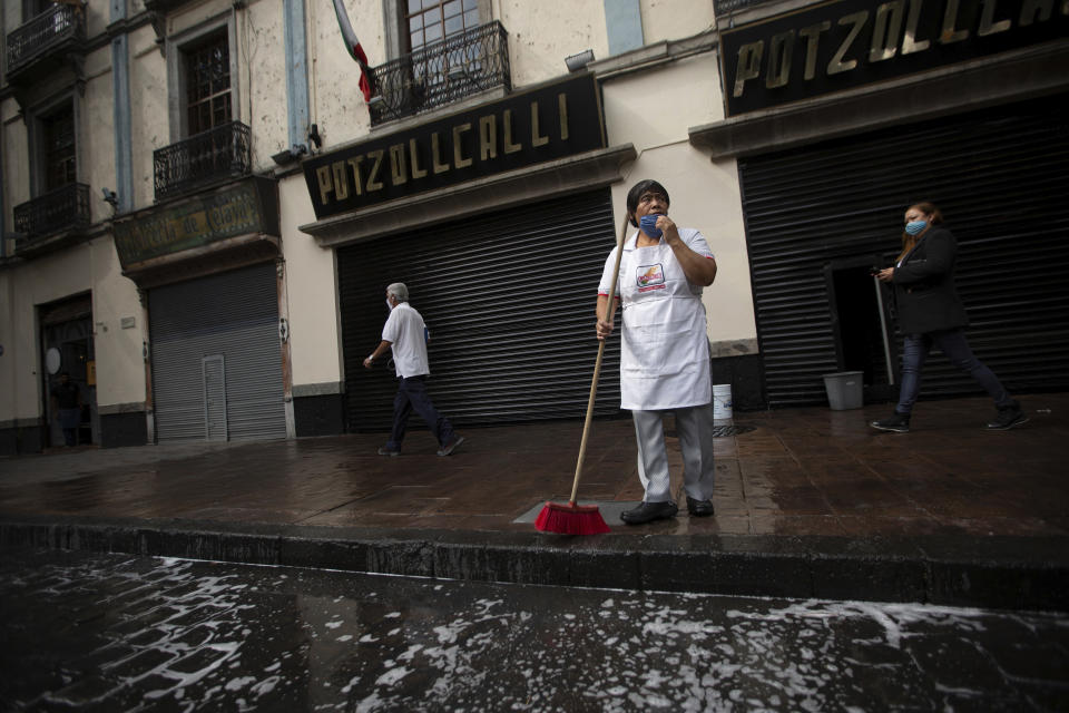 A restaurant worker cleans the sidewalk before opening for take-out ordres only, in Mexico City, Monday, June 1, 2020. While the federal government’s nationwide social distancing rule formally ended Monday, it is urging people in so-called “red” zones to maintain most of those measures — and so many people are falling ill and dying each day that those zones cover nearly the whole country. (AP Photo/Fernando Llano)