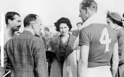 Princess Elizabeth wearing a grey reversible coat over a matching check dress talking over a game of polo she watched in Malta with the Duke of Edinburgh and the captains of the opposing teams