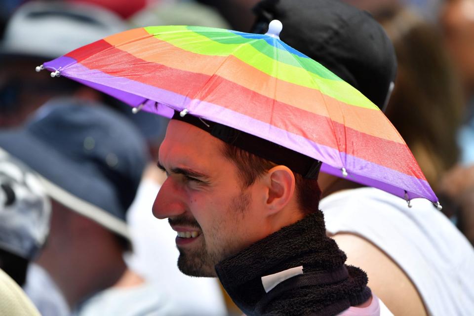 A fan uses a mini-umbrella to shelter himself from the heat as he watches Bulgaria's Grigor Dimitrov play at the Australian Open (AFP/Getty Images)