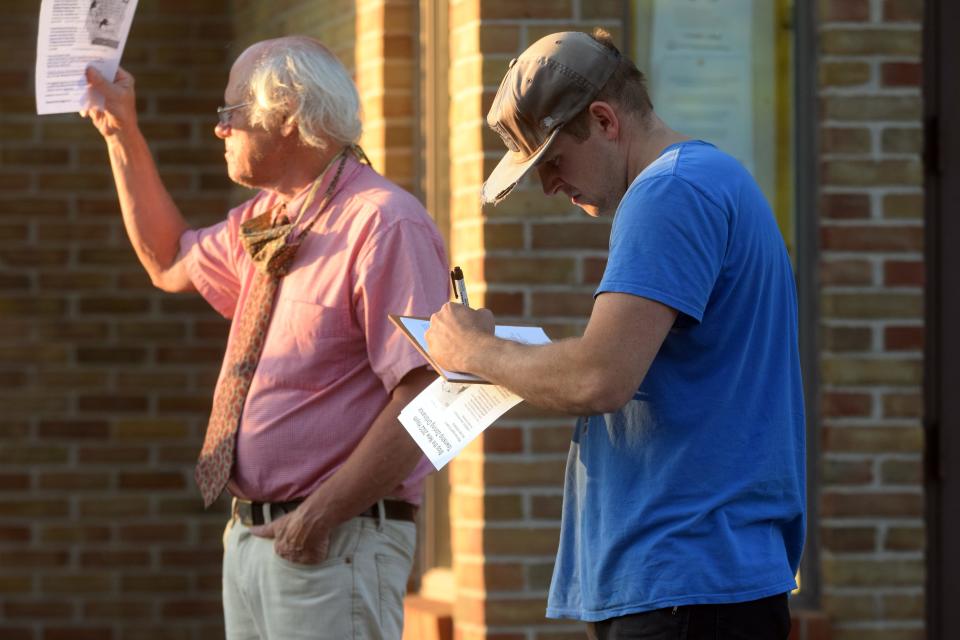 Andrew Mailloux, a resident of Bay Shore in Hayes Township, signs a petition asking the township planning commission to stop the rezoning of Hayes Township on Tuesday, Sept. 20 outside the township hall at 9195 Major Douglas Sloan Road after the township canceled the September board of trustees meeting.