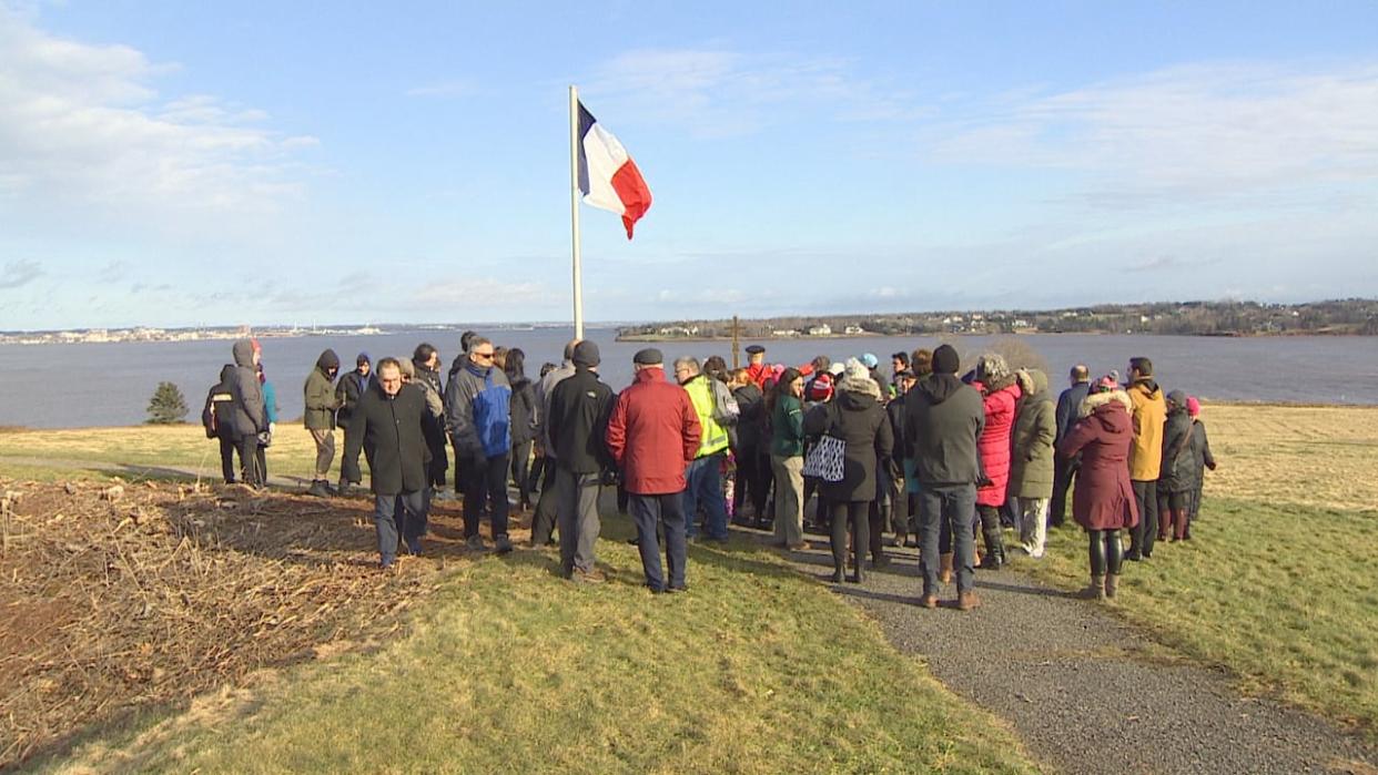 Dozens of people gathered around around the Acadian flag in Skmaqn—Port-la-Joye—Fort Amherst on Wednesday. (Rick Gibbs/CBC - image credit)