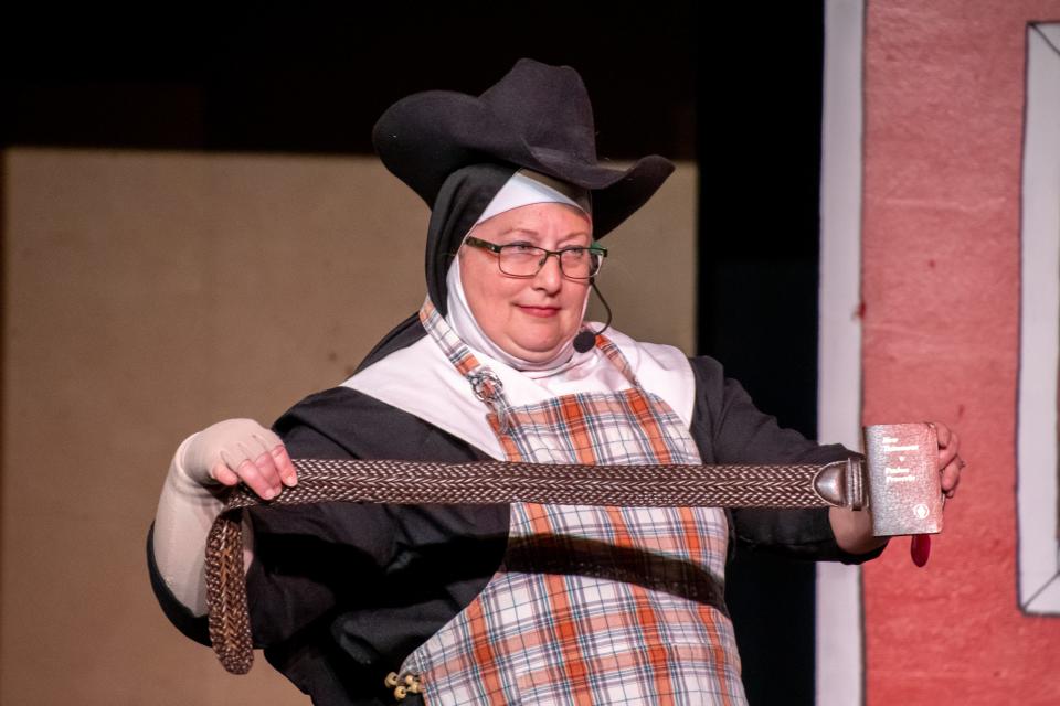 Sister Mary Wilhelm, portrayed by Christine Pyscher, displays a Bible belt to auction off to help fund Sister Amnesia's trip in the latest "Nunsense" at the Cambridge Performing Arts Centre.