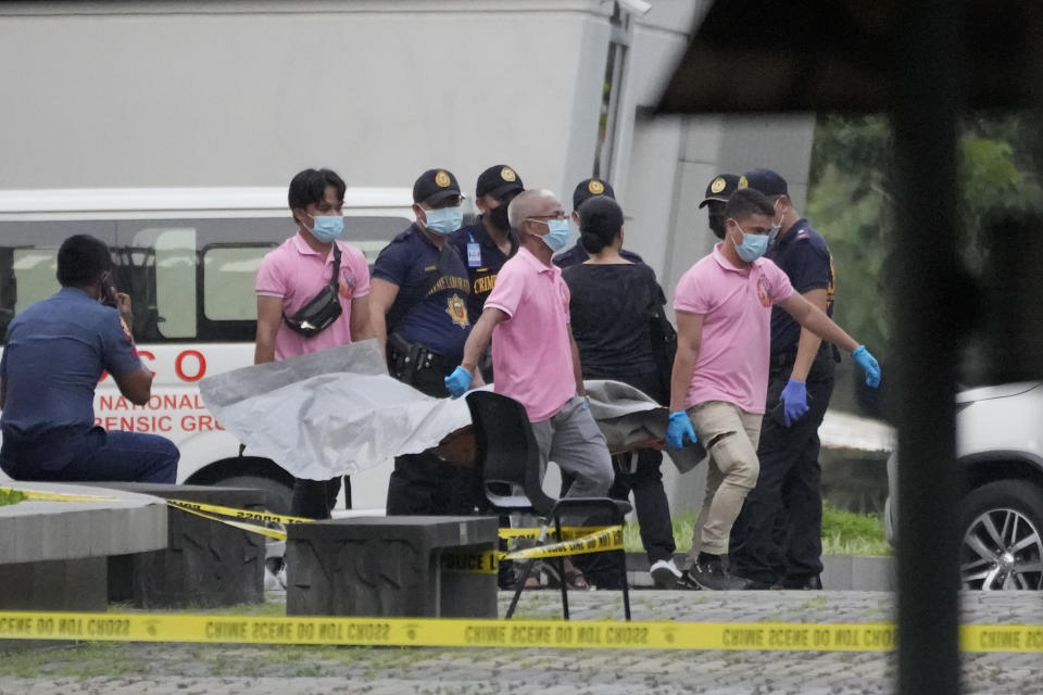 Funeral workers carry a victim's body at the Ateneo de Manila University in Quezon city, Philippines, Sunday, July 24, 2022. At least three people, including a former Philippine town mayor, were killed and another was wounded in a brazen attack on Sunday by a gunman in a university campus in the capital region, officials said. (AP Photo/Aaron Favila)