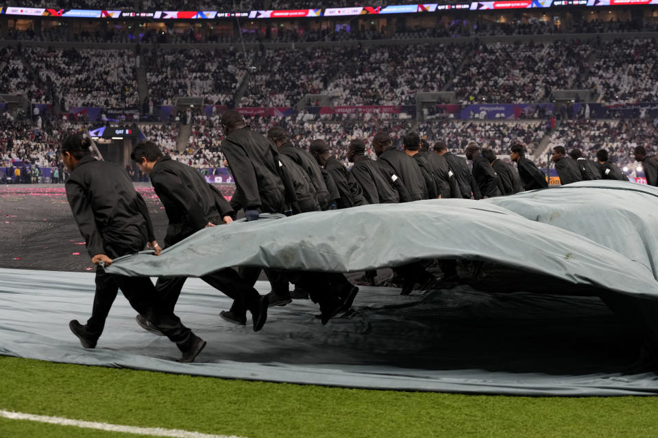 A group of migrant workers remove plastic sheets after the opening ceremony ahead of the Asian Cup Group A soccer match between Qatar and Lebanon at Lusail Stadium in Lusail, Qatar, Friday, Jan. 12, 2024. The plight of migrant workers in Qatar came under the spotlight for more than decade after the gas-rich Middle Eastern emirate was awarded the World Cup in 2010. Workers labored in the searing heat to build over $200 billion worth of stadiums and infrastructure that helped make the tournament such a success. (AP Photo/Aijaz Rahi)