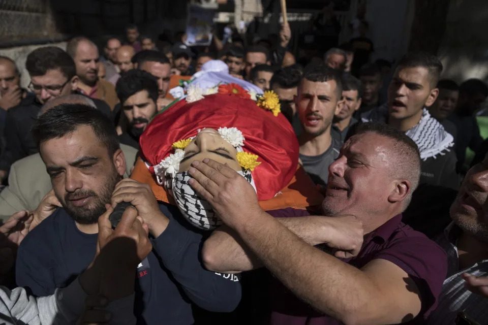 Eyad al-Soos, right carries the body of his son Sohaib al-Soos, 15, during his funeral in the West Bank city of Ramallah, Saturday, Oct. 21, 2023. Al-Soos was killed during an Israeli army raid in the town of Betunia last Friday, the Palestinian ministry of health said. (AP Photo/Nasser Nasser)
