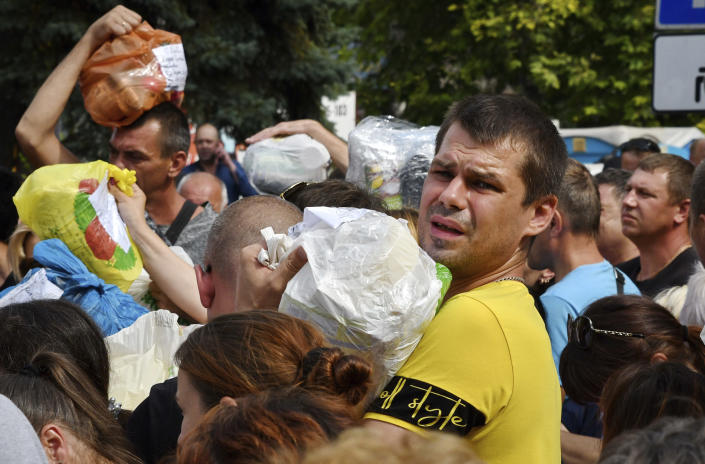 Local residents, many of whom fled the war, gather to hand out donated items such as medicines, clothes, and personal belongings to their relatives on the territories occupied by Russia, in Zaporizhzhia, Ukraine, Sunday, Aug. 14, 2022. Volunteers transport these items across the frontline and distribute them to addresses at their own risk. (AP Photo/Andriy Andriyenko)