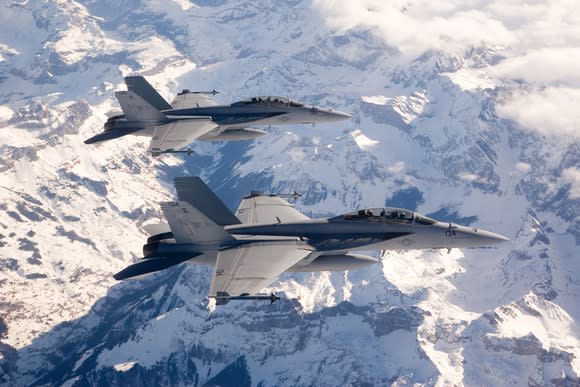 Boeing's F-18 Super Hornet flies over snow-capped mountains.