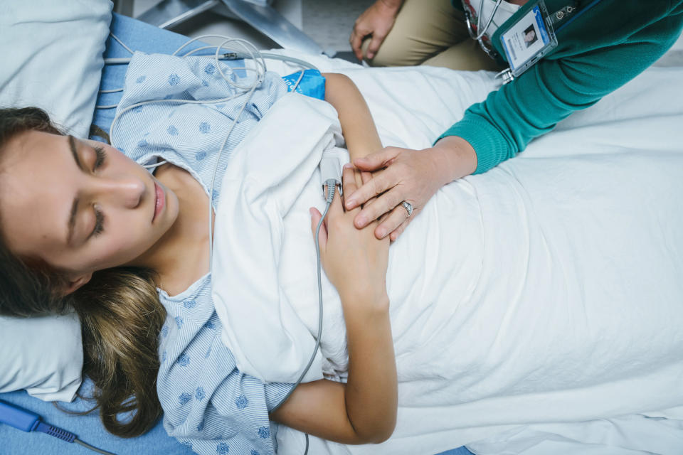 A woman asleep on her back in a hospital bed