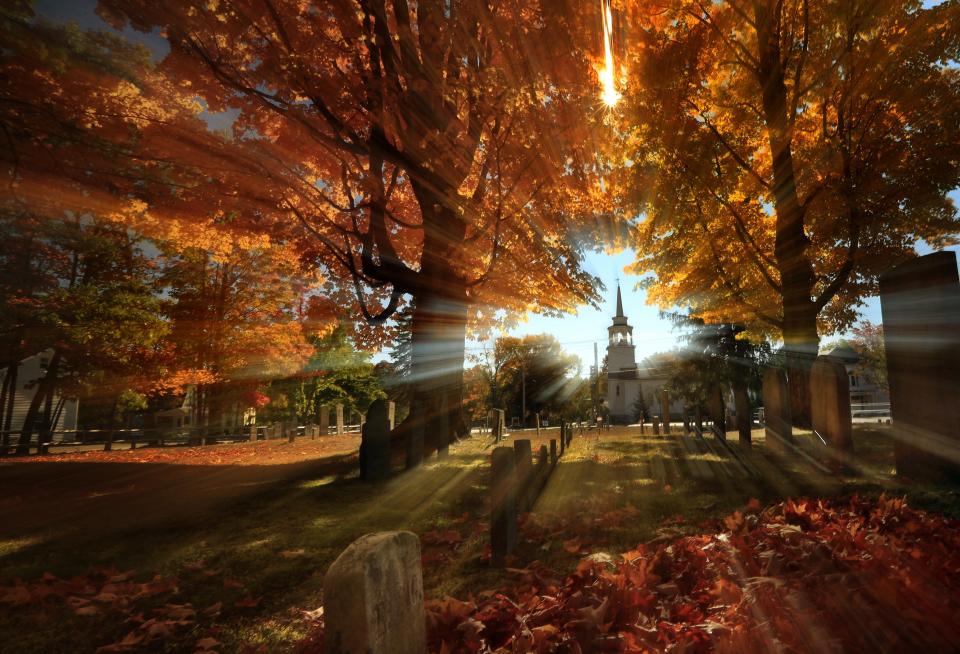 FILE - In this photo taken with a slow shutter speed, autumn's colors peak on hardwood trees in a cemetery near the Congregational Church, Monday, Oct. 10, 2016, in Cumberland, Maine. (AP Photo/Robert F. Bukaty, File)