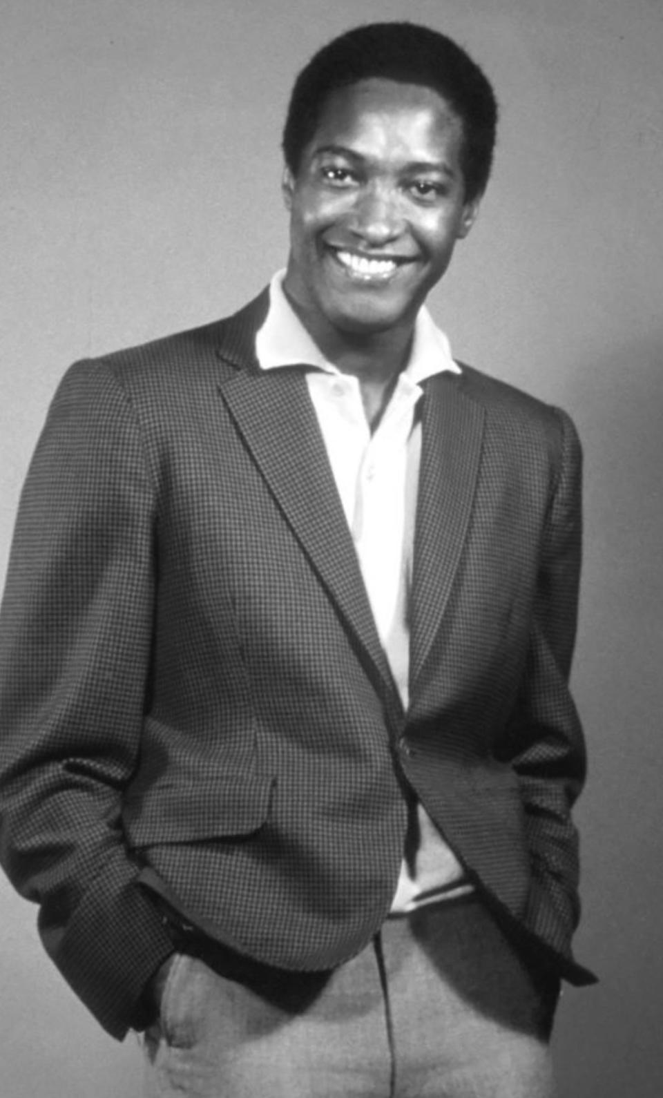 Cooke smiling while wearing a fancy blazer with an unbuttoned dress shirt underneath, early '60s