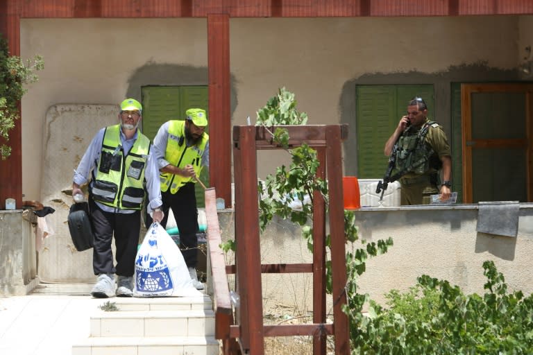 An Israeli soldier stands guard as Zaka volunteers, an emergency response team in Israel, collect human remains in a house in the Jewish settlement of Kiryat Arba in the occupied West Bank where a 13-year-old Israeli girl was fatally stabbed