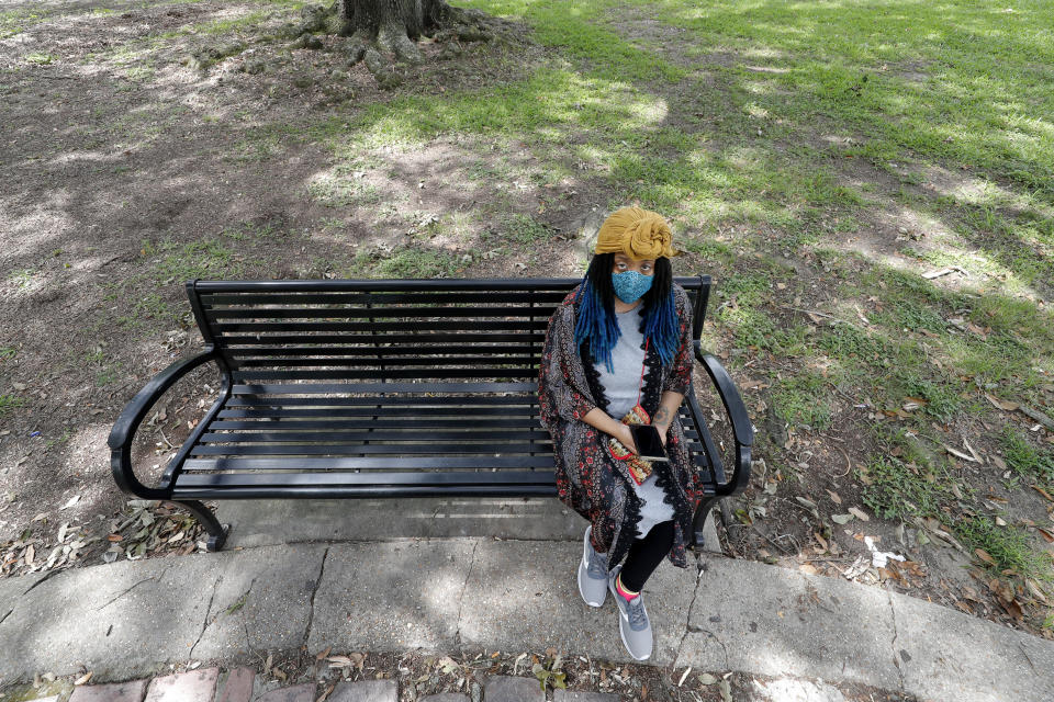 Jasmin Pierre poses for a photo with her smartphone app, in New Orleans, Thursday, July 2, 2020. Pierre, who survived multiple suicide attempts, doesn't want people struggling alone. She created The Safe Place, a free Black-oriented mental health app that's seen more signups during the pandemic. (AP Photo/Gerald Herbert)