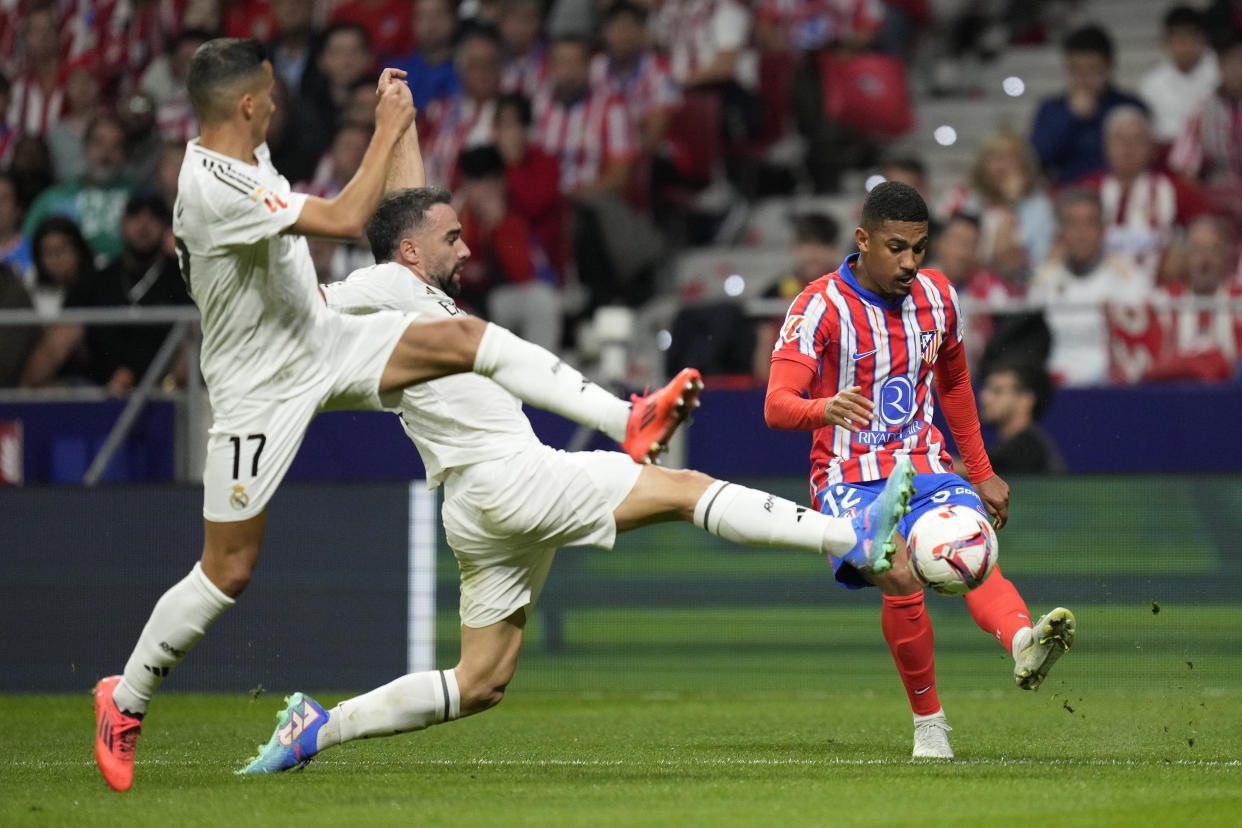 Atletico Madrid's Samuel Lino sends a cross by Real Madrid's Lucas Vazquez, left, and Dani Carvajal during the La Liga soccer match between Atletico Madrid and Real Madrid at the Metropolitano stadium in Madrid, Spain, Sunday, Sept. 29, 2024. (AP Photo/Bernat Armangue)