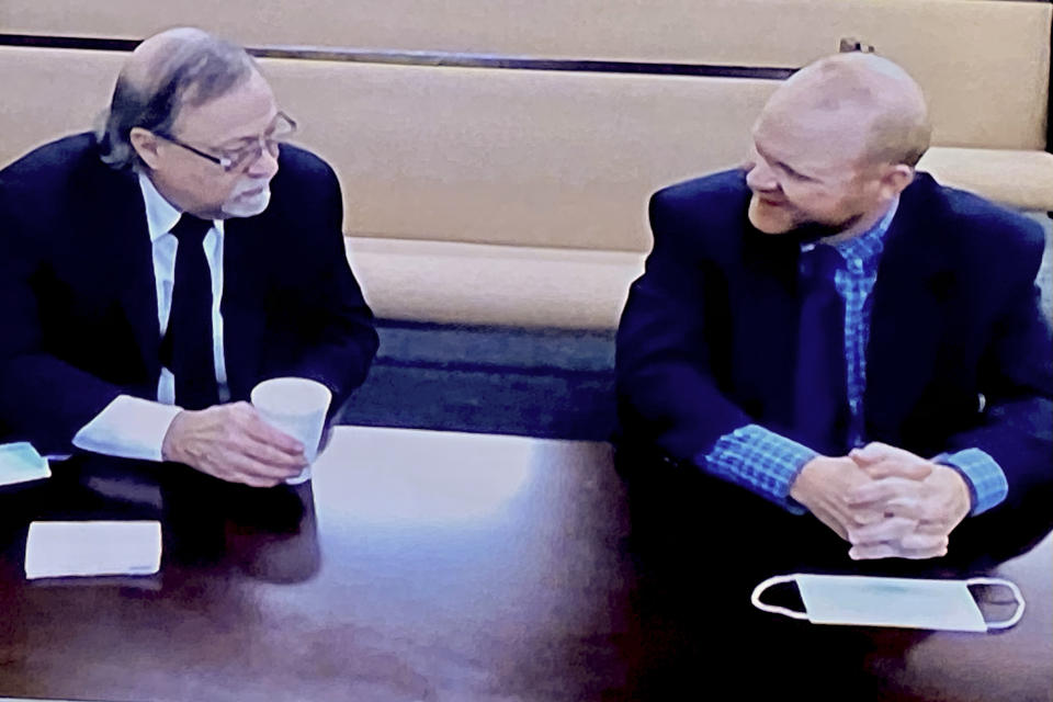 In this image made from video, from left, father and son, Gregory and Travis McMichael, accused in the shooting death of Ahmaud Arbery in Georgia on Feb. 2020, speak to each other via closed circuit tv in the Glynn County Detention center in Brunswick, Ga., on Thursday, Nov. 12, 2020. The McMichaels chased and fatally shot Ahmaud Arbery, a 25-year-old Black man, after they spotted him running in their neighborhood just outside the port city of Brunswick. (AP Photo/Lewis Levine)