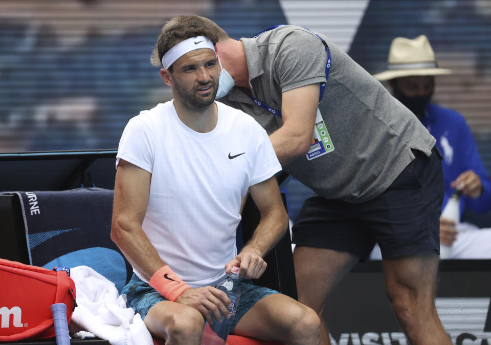 Bulgaria's Grigor Dimitrov receives treatment during this quarterfinal against Russia's Aslan Karatsev at the Australian Open tennis championship in Melbourne, Australia, Tuesday, Feb. 16, 2021.(AP Photo/Hamish Blair)