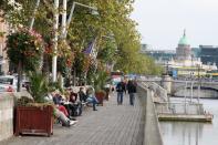 People relax on the riverfront in Dublin.