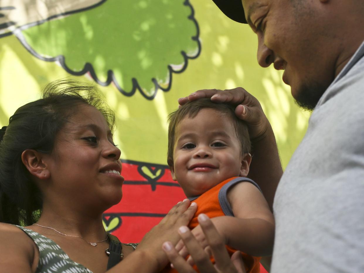 Adalicia Montecino holds her year-old son Johan Bueso Montecinos, who became a poster child for the US policy of separating immigrants and their children, as his father Rolando Bueso Castillo caresses Johan's head: AP Photo/Esteban Felix