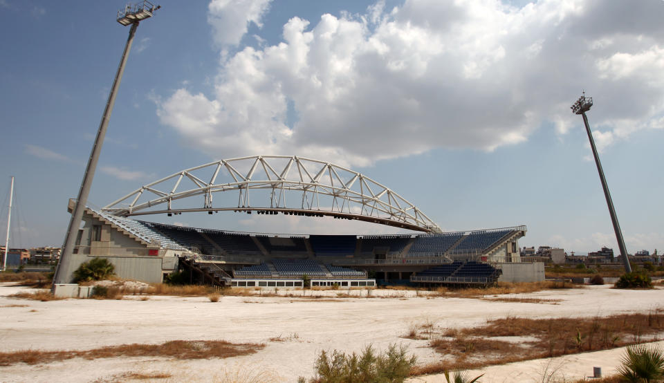 FILE - In this Thursday, Aug. 2, 2012, file photo, the Olympic beach volleyball lies abandoned in southern Athens. The legacy of Athens’ Olympics has stirred vigorous debate, and Greek authorities have been widely criticized for not having a post-Games plan for the infrastructure. While some of the venues built specifically for the games have been converted for other uses, many are underused or abandoned, and very few provide the state with any revenue. Some critics even say that the multibillion dollar cost of the games played a modest role in the nation’s 2008 economic meltdown. (AP Photo/Thanassis Stavrakis)