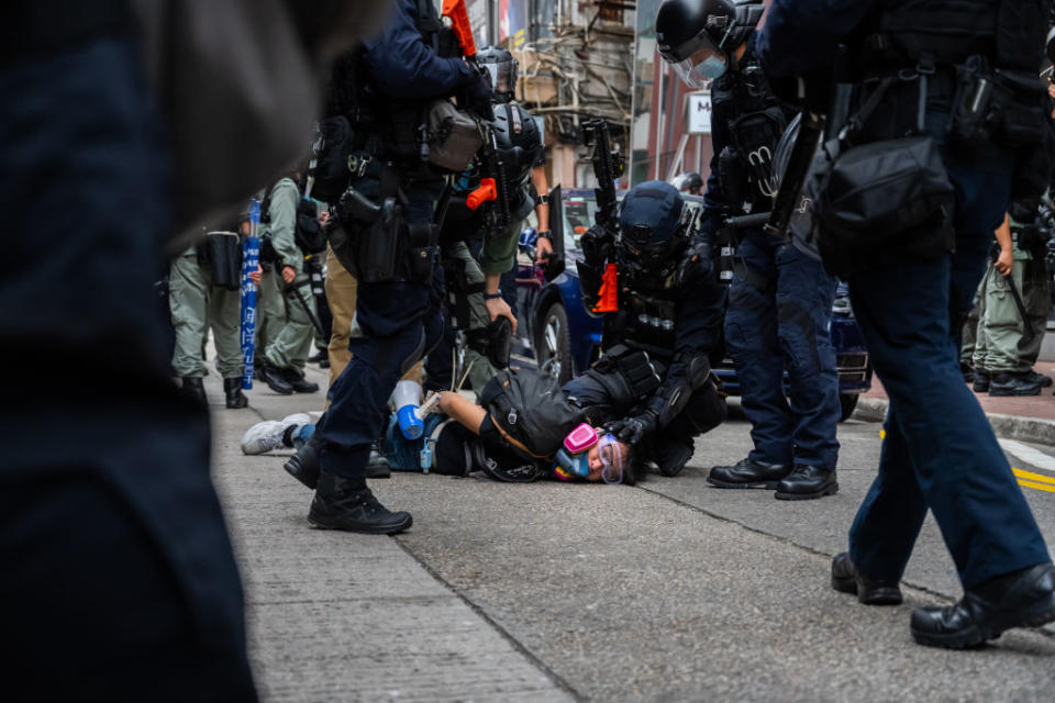 A pro-democracy supporter is detained by riot police Sunday. Source: Getty