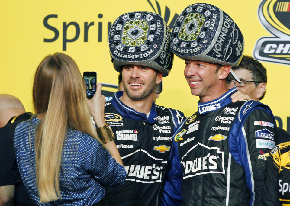 FILE - Chandra Johnson takes photos of her husband, Jimmie Johnson, center, and his crew chief, Chad Knaus, after Jimmie won his sixth NASCAR Sprint Cup Series championship in Homestead, Fla., Nov. 17, 2013. Jimmie Johnson and Chad Knaus were paired at Hendrick Motorsports in late 2001 as two unproven racers that team owner Rick Hendrick believed could be successful together in NASCAR’s top series. Their success was immediate and unstoppable as the duo won a record-tying seven Cup titles that included an unprecedented five in a row. (AP Photo/Terry Renna, File)