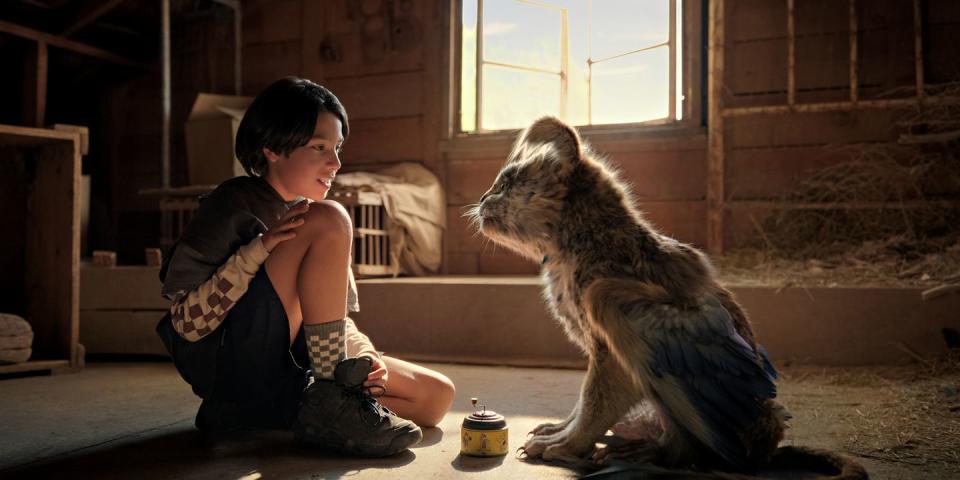 a kid sits calmly next to a furry creature in a scene from chupa, a good housekeeping pick for best kids' movies 2023